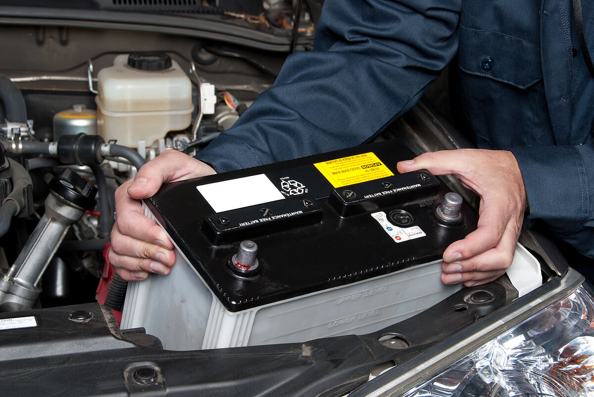 Contrôles saisonniers A car mechanic replaces a battery.